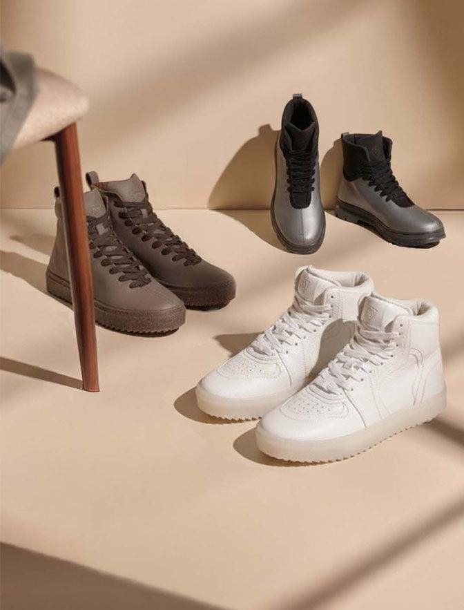 J Town high tops and boots on a warm studio set